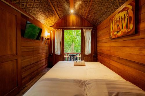 1 dormitorio con 1 cama en una habitación de madera en Arkamaya Kusuma Resort en Yogyakarta