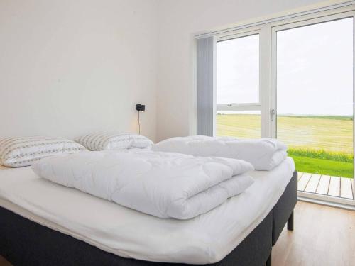 Cama blanca grande en habitación con ventana grande en Holiday home Lemvig XLII, en Lemvig