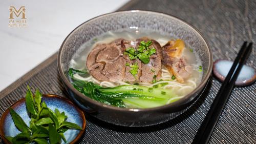 a bowl of soup with meat and vegetables on a table at VM Hotel in Phnom Penh