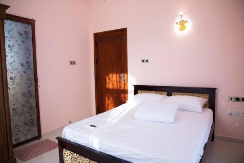 a bedroom with a bed with white sheets and pillows at WIMAL PALACE in Jaffna