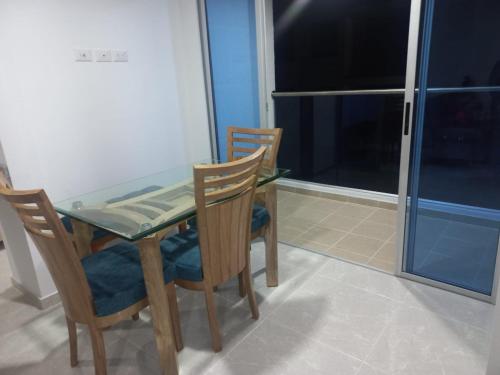 a table and chairs with a glass table and a window at Hermoso apartamento con piscina ubicado cerca a los principales centros comerciales in Ibagué