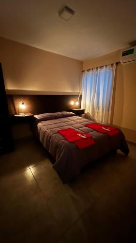 ein Schlafzimmer mit einem Bett mit zwei roten Handtüchern darauf in der Unterkunft Las Rejas Departamento in San Fernando del Valle de Catamarca
