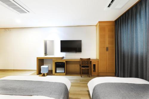 a hotel room with two beds and a flat screen tv at Paju Golden Hill in Paju