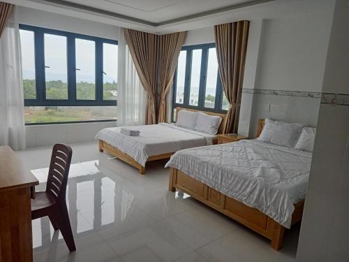 a bedroom with two beds and a desk and a window at HOTEL VTV DỐC LẾT in Ninh Hòa