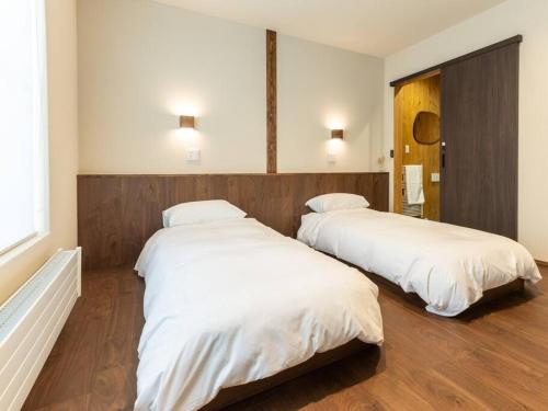2 camas en una habitación con sábanas blancas en Oguma House en Nozawa Onsen