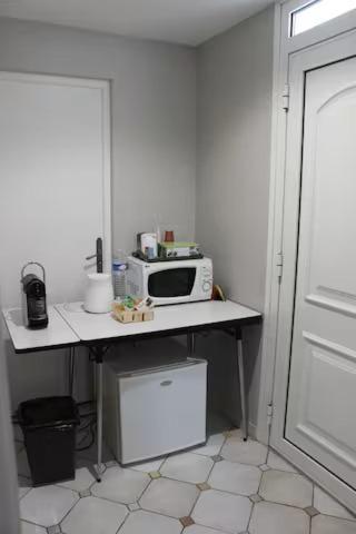 eine Küche mit einem Tisch und einer Mikrowelle in der Unterkunft chambre avec entrée indépendante in Saint-Priest