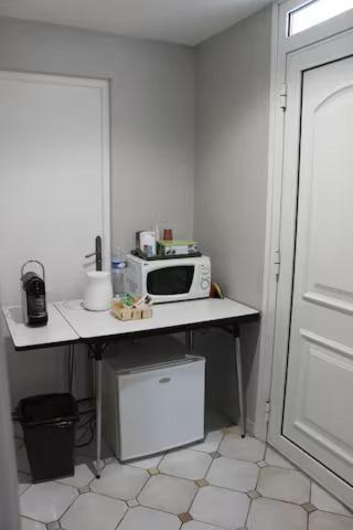 une cuisine avec une table et un four micro-ondes. dans l'établissement chambre avec entrée indépendante, à Saint-Priest