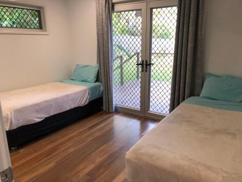 a room with two beds and a sliding glass door at Endeavour Reach in Cooktown