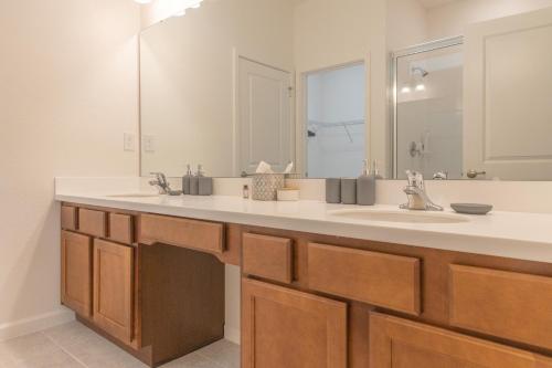 a bathroom with a sink and a large mirror at Summer Fun - Waterfront 8BR Home with Private Pool! in Kissimmee