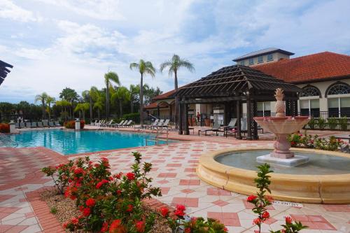 a swimming pool with a fountain in front of a building at Summer Fun - Waterfront 8BR Home with Private Pool! in Kissimmee