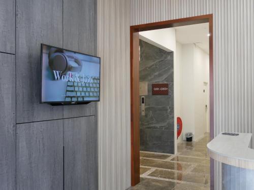 a television on the wall of a room with a hallway at Pantai Regal City Hotel in Kuantan