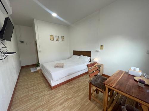 Schlafzimmer mit einem Bett, einem Schreibtisch und einem Tisch in der Unterkunft Muji House & Cafe' in Non Sang