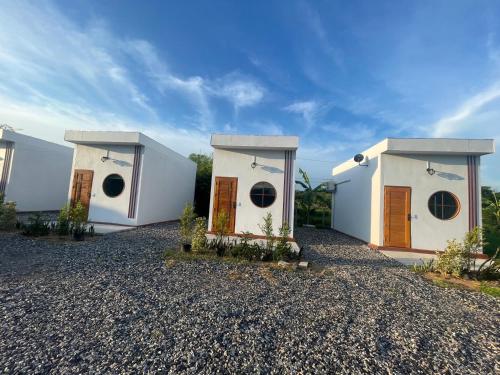 two white houses with brown doors on a gravel driveway at Muji House Resort in Non Sang