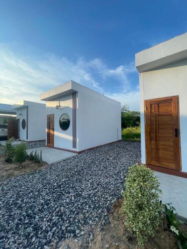 a white house with a door on the side of it at Muji House Resort in Non Sang