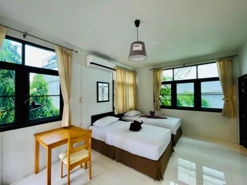 a bedroom with two beds and a desk and windows at home near MRT Tha Phra Villa sookkasem in Bangkok Yai