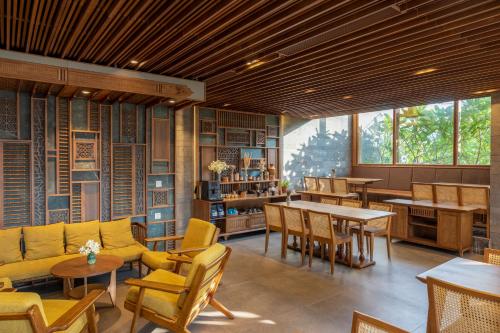 a restaurant with yellow furniture and tables and windows at Bonny Boutique Hotel Da Nang in Da Nang