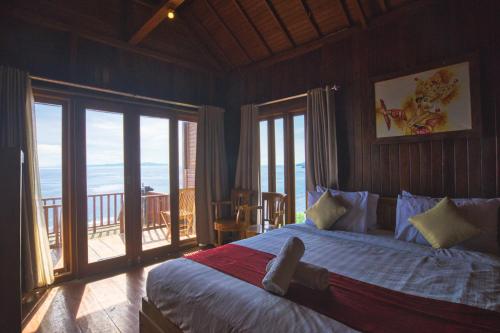 een slaapkamer met een bed en uitzicht op de oceaan bij Manta Cottage Seaview Plus in Nusa Penida