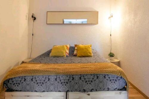 een slaapkamer met een groot bed met gele kussens bij Le petit Marc in Kingersheim