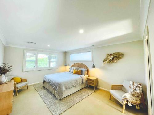 um quarto com uma cama, uma cadeira e uma janela em Kookaburra House - Terrigal Beach em Terrigal