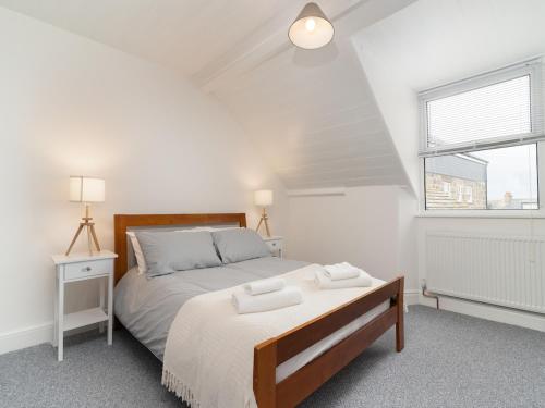 a white bedroom with a large bed and a window at Bright~ Town Center~ 2 bed~Penzance in Penzance