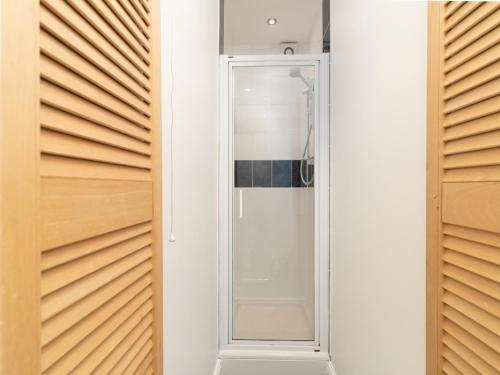 a glass shower in a bathroom with wooden doors at Bright~ Town Center~ 2 bed~Penzance in Penzance