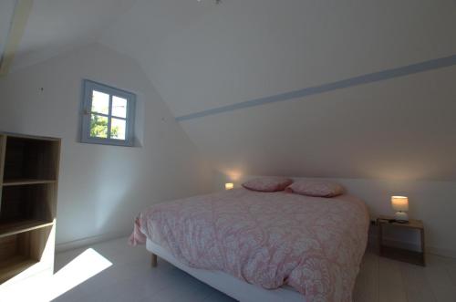 een witte slaapkamer met een bed en een raam bij Le paradis des ecureuils 
