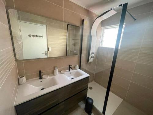 W łazience znajduje się umywalka, lustro i prysznic. w obiekcie L appart dans les Nuages - Climatisé - Piscine - Vues panoramiques - Proche aéroport et Université w mieście Sainte-Clotilde