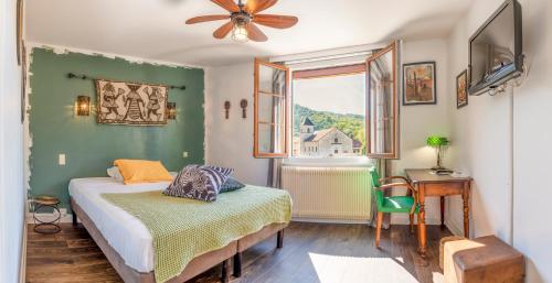 a bedroom with a bed and a table and a window at Hotel-Restaurant Le Sorgia in Bellegarde-sur-Valserine