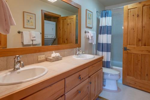 uma casa de banho com 2 lavatórios, um WC e um espelho. em Bridgepoint Condo 08 em Ketchum