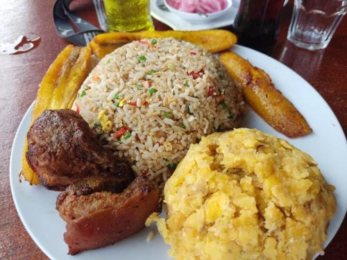 a plate of food with rice and meat and bread at Garrison Alojamiento , selva y Turismo y Comida in Tingo María