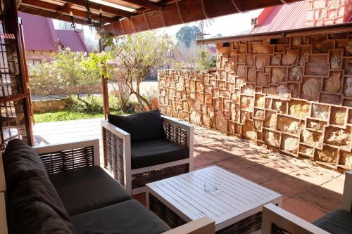 a patio with two chairs and a table and a stone wall at Mountain View Cottage in Dullstroom