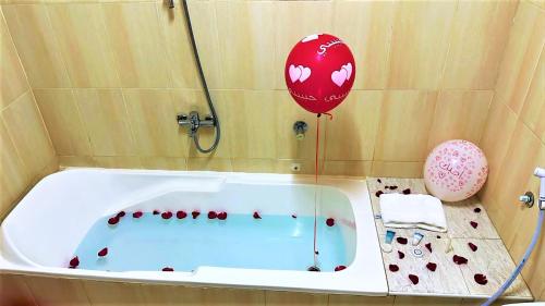 a red balloon and a tub in a bathroom at Bahla Hotel Apartments in Bahlāʼ