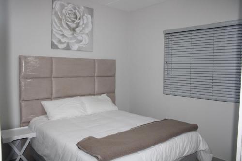 Cama en habitación blanca con ventana en Stylish Apartment in Fourways, en Sandton