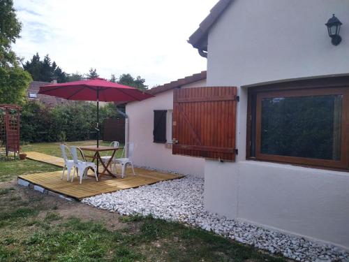 a wooden deck with a table and an umbrella at La Tanière des Pandas in Chabris