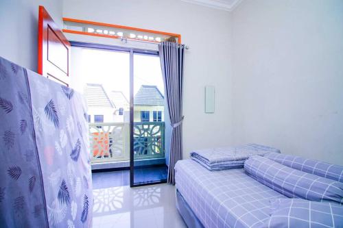 ein Schlafzimmer mit einem Bett und einem großen Fenster in der Unterkunft Harsari Syariah with Karaoke and Balcony in Batu