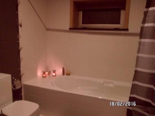 a bathroom with a tub and a toilet and candles at Maison proche de la mer in Murtosa