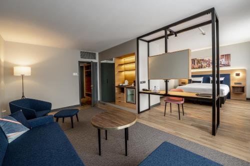 فندق غريشام بيلسون بروكسل في بروكسل: غرفه فندقيه بسرير واريكه وطاولة