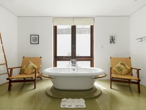 a bath tub in a room with two chairs at Casa Evaliza in Seminyak