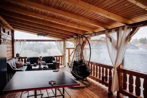 a room with a table and a hammock on a balcony at Cabana Refugiul Montan Belis in Beliş