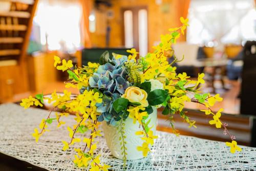 a white vase filled with yellow flowers on a table at Cabana Refugiul Montan Belis in Beliş