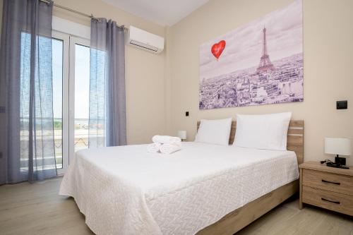 a bedroom with a white bed and a large window at GIANNI'S COMFORT CITY APARTMENT in Alexandroupoli