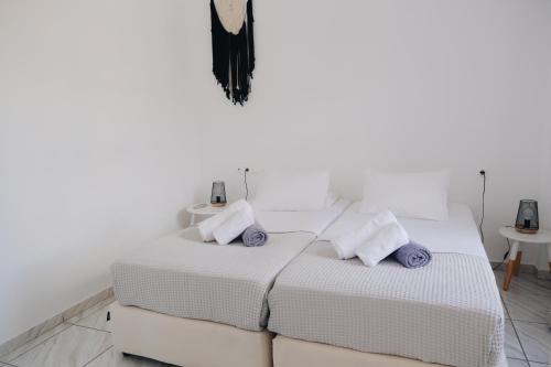 two beds in a room with white walls and purple pillows at Paradise Apartments Studios in Mylopotas
