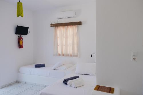 a living room with two white beds and a tv at Paradise Apartments Studios in Mylopotas
