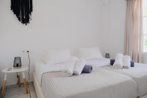 two beds in a white room with towels on them at Paradise Apartments Studios in Mylopotas