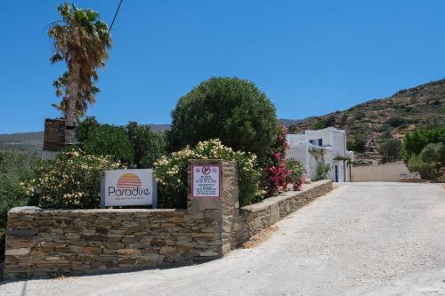 a sign on a stone wall next to a road at Paradise Apartments Studios in Mylopotas
