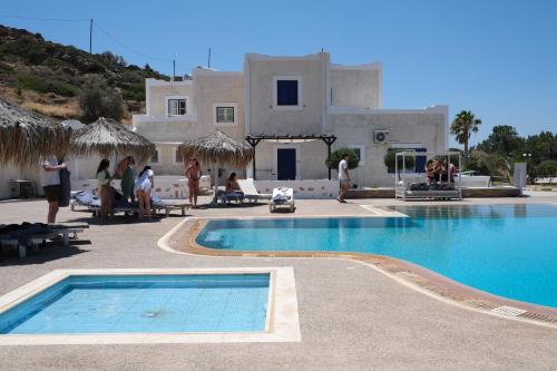 a swimming pool in front of a house with people standing around it at Paradise Apartments Studios in Mylopotas