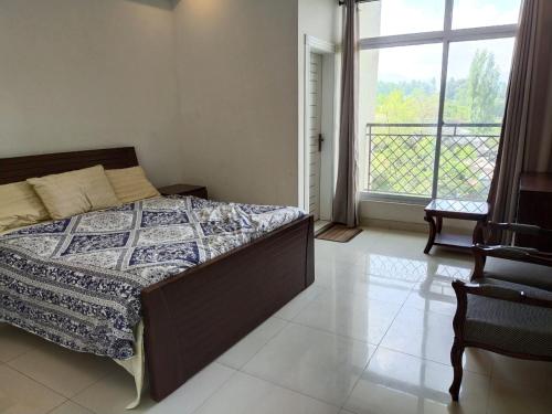 a bedroom with a bed and a large window at Bhurban Continental Apartment 45-F in Bhurban
