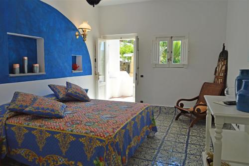 een slaapkamer met een bed, een tafel en een stoel bij Hotel Oasi in Panarea