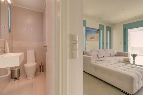 - un salon blanc avec un canapé et un lavabo dans l'établissement Ouzo Panoramic Houses 1, with private pool, à Plomári