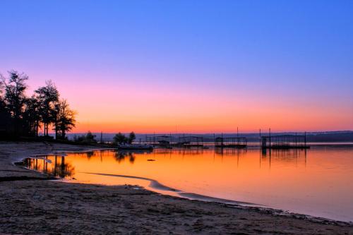 a sunset over a body of water with a dock at The Perfect Porch Retreat in Eufaula
